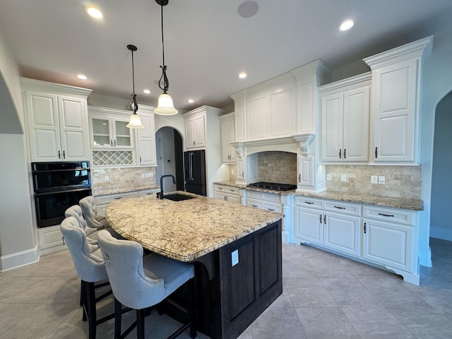 kitchen featuring backsplash, white cabinetry, black appliances, and an island with sink