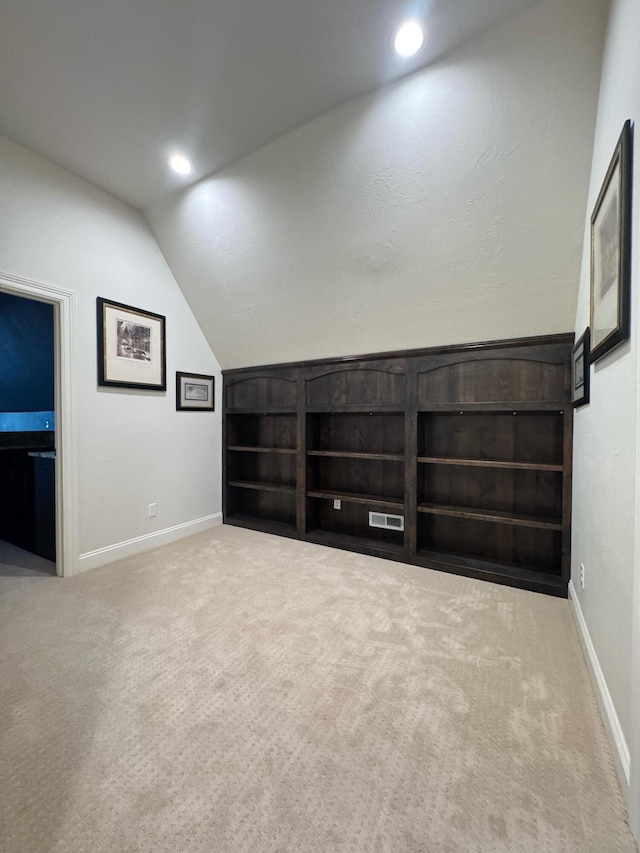 bonus room featuring built in shelves, carpet, and vaulted ceiling