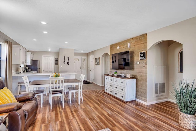 dining space featuring light hardwood / wood-style flooring and wooden walls