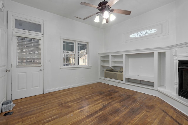 unfurnished living room featuring a wall mounted air conditioner, ceiling fan, and dark wood-type flooring