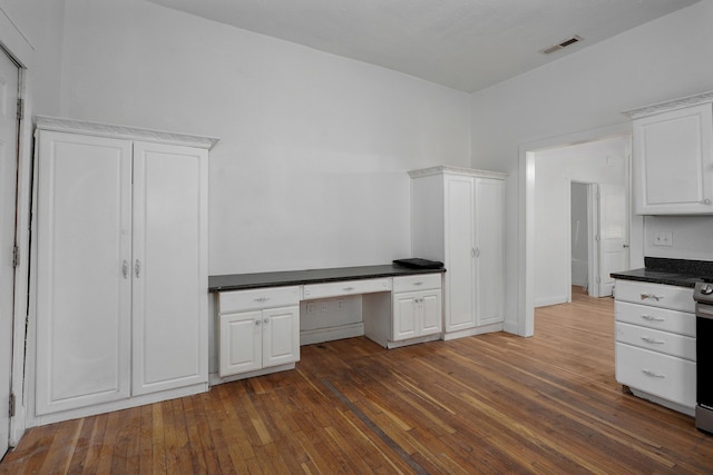 unfurnished office featuring dark hardwood / wood-style floors and built in desk