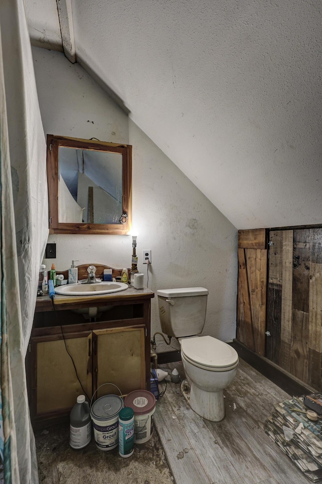 bathroom with toilet, a textured ceiling, hardwood / wood-style flooring, vanity, and lofted ceiling