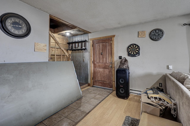 interior space with light hardwood / wood-style floors, baseboard heating, and a textured ceiling