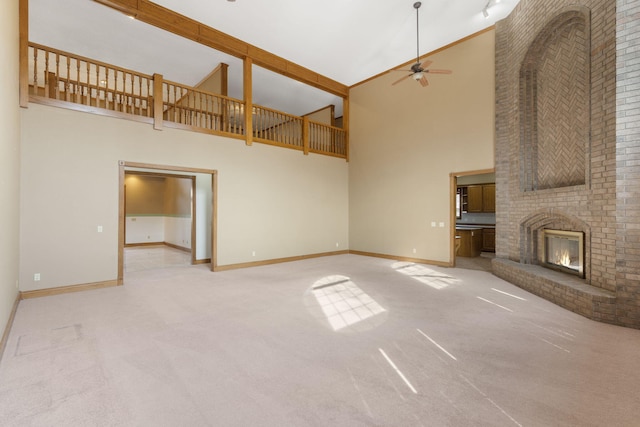 unfurnished living room featuring ceiling fan, light carpet, a brick fireplace, and a towering ceiling