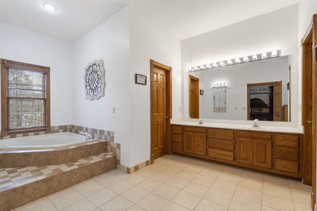 bathroom featuring vanity, tile patterned flooring, a textured ceiling, and tiled tub