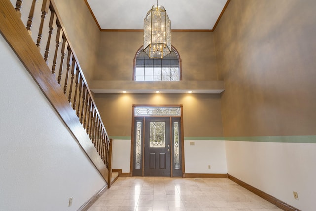 foyer entrance with crown molding, an inviting chandelier, a high ceiling, and a wealth of natural light