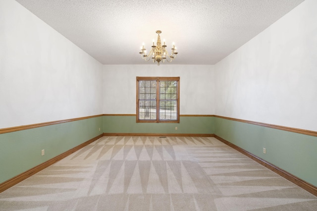 unfurnished room with carpet flooring, a textured ceiling, and a chandelier