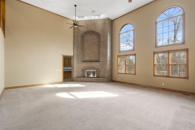 unfurnished living room featuring crown molding, ceiling fan, light carpet, and a brick fireplace