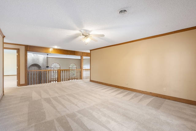 carpeted spare room with ceiling fan, ornamental molding, and a textured ceiling