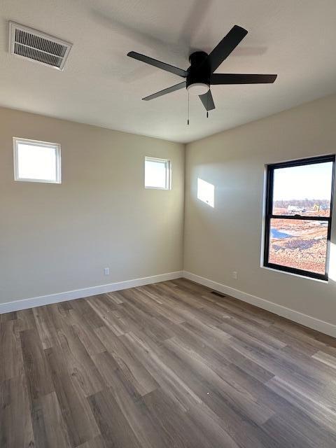 spare room with hardwood / wood-style flooring, a wealth of natural light, and ceiling fan