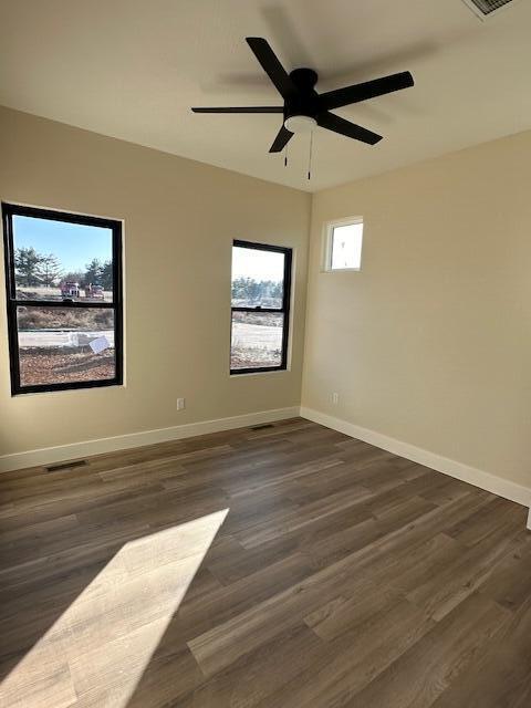 empty room with ceiling fan and dark hardwood / wood-style flooring