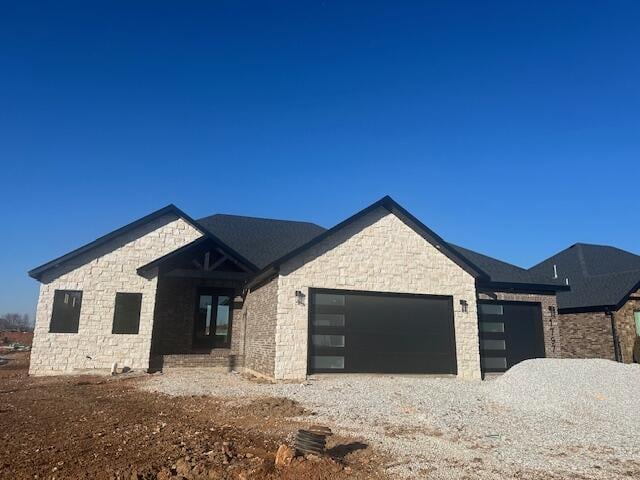 view of front of property featuring a garage and gravel driveway