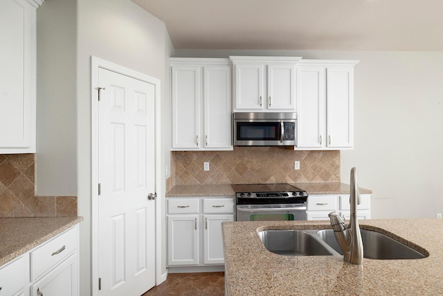 kitchen featuring light stone countertops, appliances with stainless steel finishes, white cabinetry, sink, and backsplash