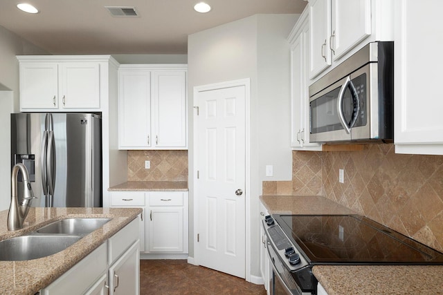 kitchen featuring dark tile patterned floors, white cabinets, sink, backsplash, and stainless steel appliances