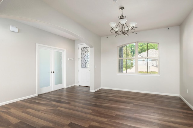 foyer entrance with a notable chandelier, french doors, and dark wood-type flooring