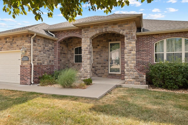 view of exterior entry featuring a garage and a yard