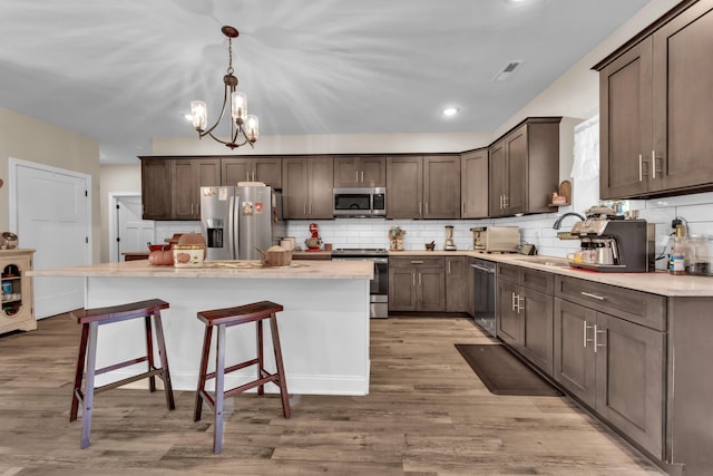 kitchen featuring a kitchen island, light hardwood / wood-style flooring, hanging light fixtures, and stainless steel appliances