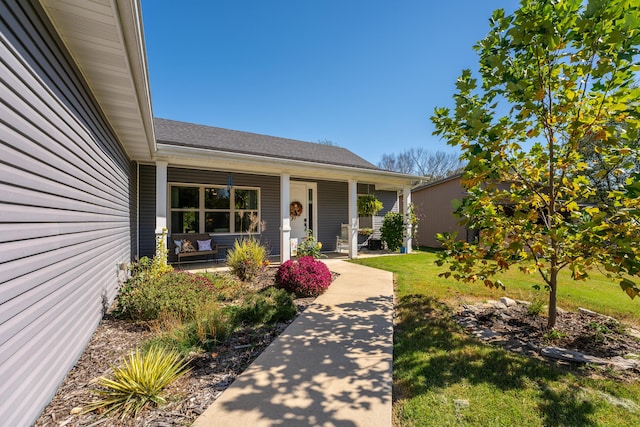 view of exterior entry featuring a porch and a lawn