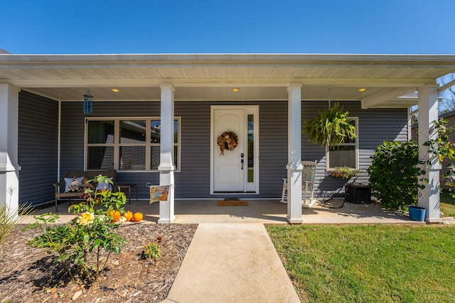 doorway to property with covered porch and a lawn