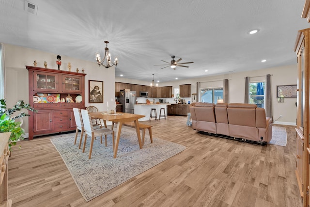 dining area featuring light hardwood / wood-style floors and ceiling fan with notable chandelier