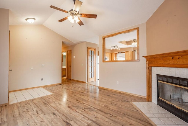 unfurnished living room with ceiling fan, a fireplace, vaulted ceiling, and light wood-type flooring