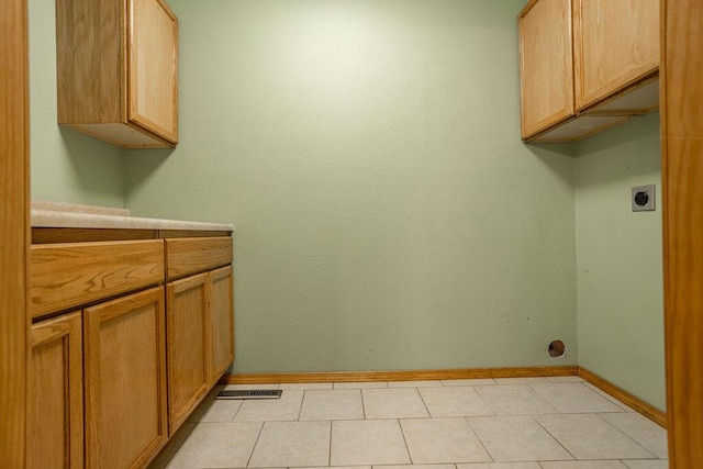 clothes washing area with cabinets, light tile patterned floors, and hookup for an electric dryer