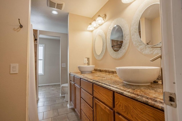 bathroom with tile patterned flooring, vanity, and toilet