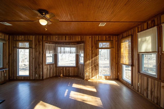 unfurnished sunroom featuring a healthy amount of sunlight, ceiling fan, and wood ceiling