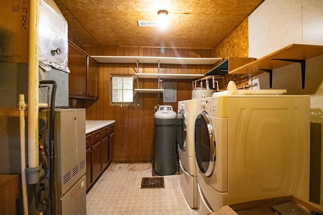 clothes washing area with wood walls, cabinets, and washer and dryer