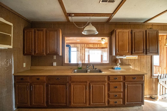 kitchen with ceiling fan, sink, and wooden walls