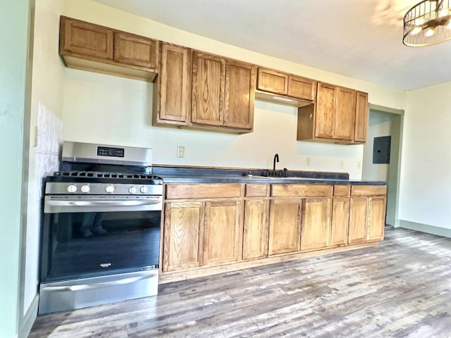 kitchen with electric panel, sink, light hardwood / wood-style flooring, and stainless steel gas range oven