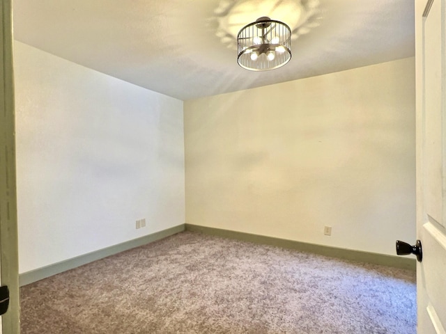 carpeted spare room with a notable chandelier