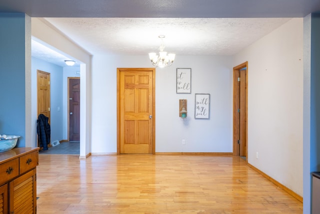 dining area featuring light wood-style flooring, a chandelier, and a textured ceiling