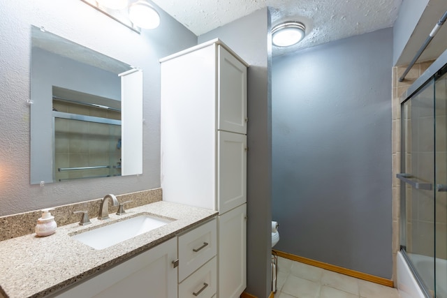 bathroom featuring baseboards, bath / shower combo with glass door, toilet, vanity, and a textured ceiling