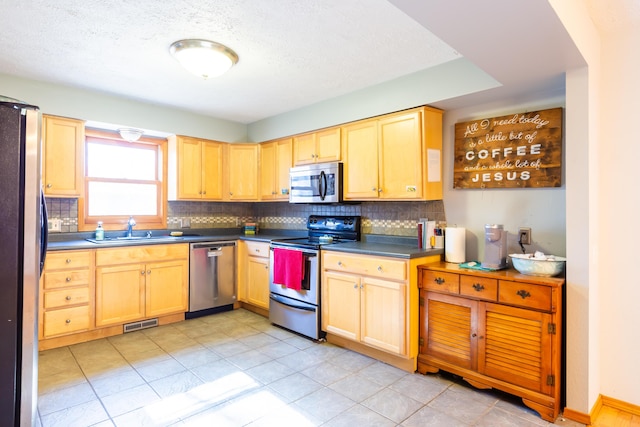 kitchen with visible vents, light brown cabinets, a sink, backsplash, and appliances with stainless steel finishes