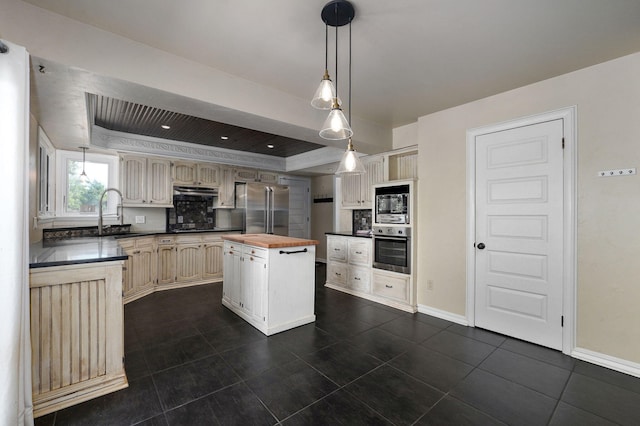 kitchen with sink, wooden counters, a center island, a raised ceiling, and stainless steel appliances