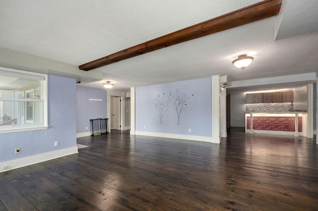 unfurnished living room featuring dark hardwood / wood-style flooring, beam ceiling, and a textured ceiling