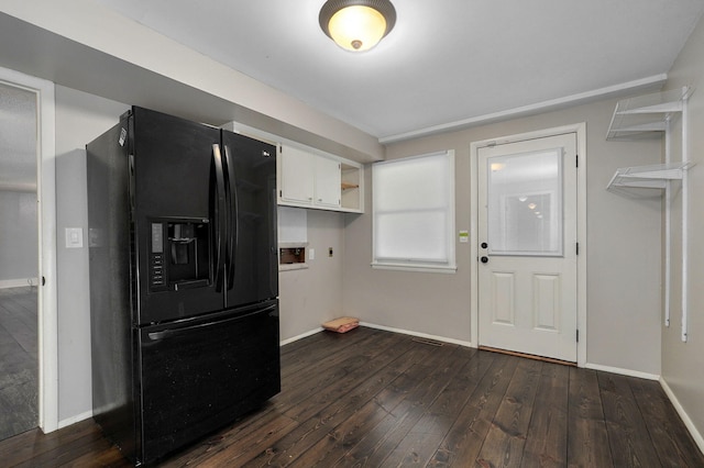 kitchen with black fridge, white cabinetry, and dark hardwood / wood-style flooring