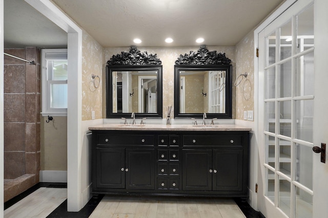 bathroom with tiled shower, vanity, and wood-type flooring