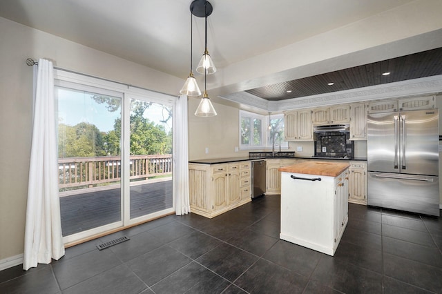 kitchen featuring appliances with stainless steel finishes, butcher block counters, sink, hanging light fixtures, and a center island