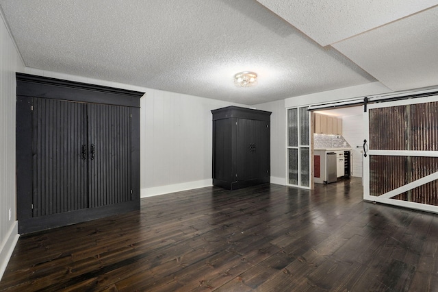 interior space with dark hardwood / wood-style floors, a barn door, and a textured ceiling