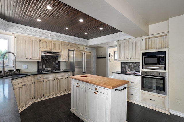 kitchen featuring sink, wood ceiling, appliances with stainless steel finishes, a raised ceiling, and a kitchen island