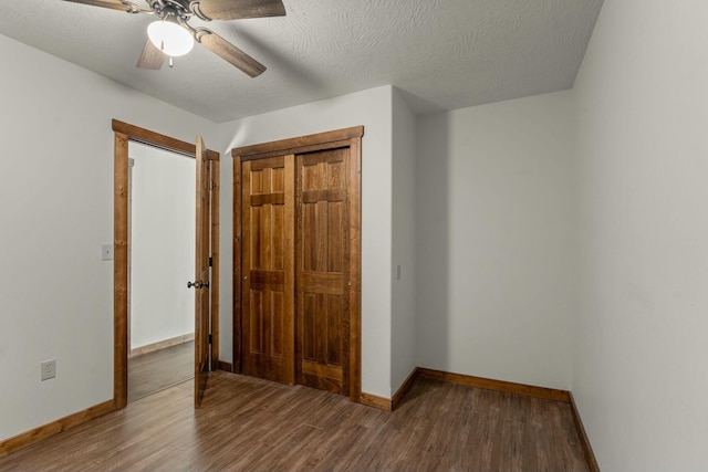 unfurnished bedroom with ceiling fan, hardwood / wood-style floors, a closet, and a textured ceiling