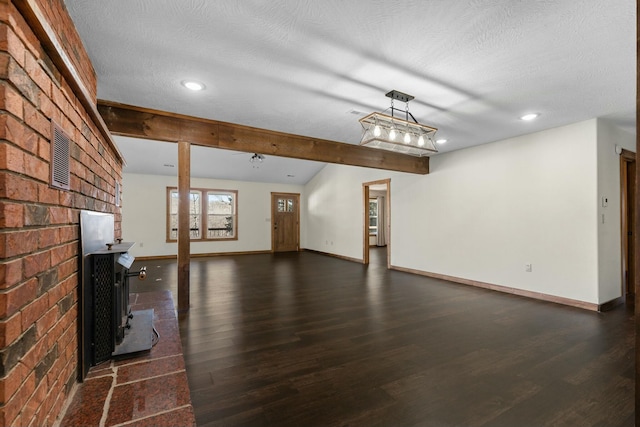 unfurnished living room featuring a brick fireplace, dark wood-type flooring, beamed ceiling, and a textured ceiling