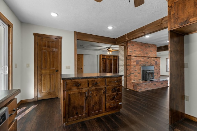 kitchen featuring dark wood-type flooring, ceiling fan, beam ceiling, and a textured ceiling