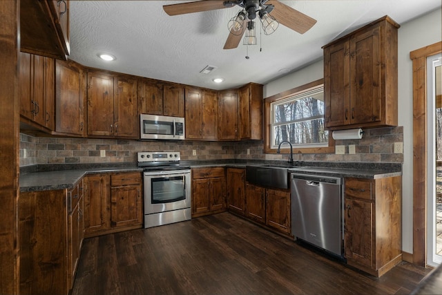 kitchen featuring dark hardwood / wood-style flooring, sink, backsplash, and appliances with stainless steel finishes