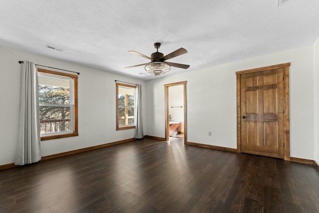 unfurnished room featuring ceiling fan, a healthy amount of sunlight, dark hardwood / wood-style floors, and a textured ceiling