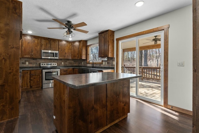 kitchen with stainless steel appliances, ceiling fan, dark hardwood / wood-style flooring, and decorative backsplash