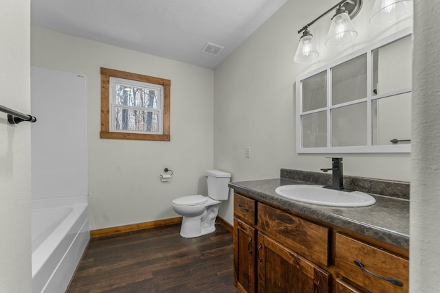 bathroom with vanity, toilet, hardwood / wood-style floors, and a textured ceiling