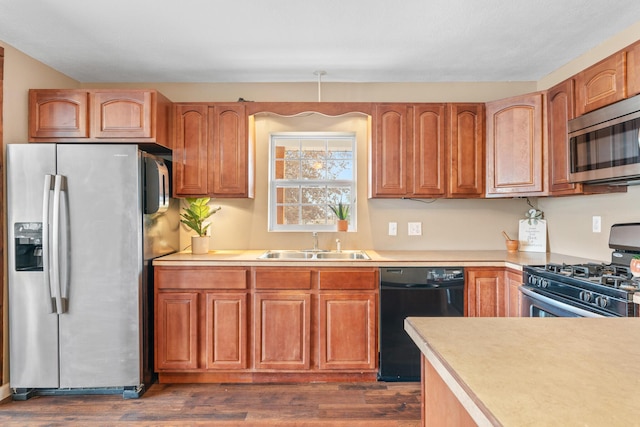 kitchen with a sink, light countertops, brown cabinetry, stainless steel appliances, and dark wood-style flooring